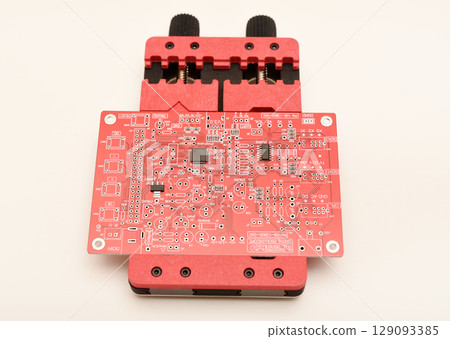 Universal professional holder for circuit boards and microchips. A red soldering circuit board in the holder. 129093385
