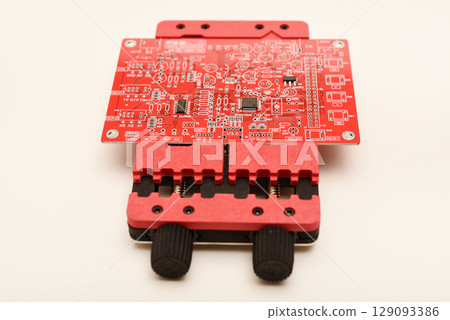 Universal professional holder for circuit boards and microchips. A red soldering circuit board in the holder. 129093386