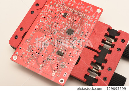 Universal professional holder for circuit boards and microchips. A red soldering circuit board in the holder. 129093399