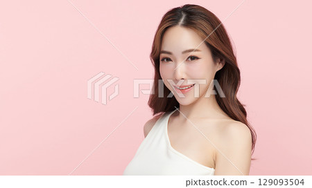 A beautiful young Asian woman with clean, fresh skin against a pink background. Skincare, facial treatment, cosmetology, beauty, and spa. An elegant portrait of an Asian woman. 129093504
