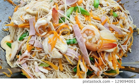 A close-up shot of stir-fried noodles with ham, shrimp and colorful vegetables 129094001