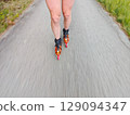 Legs in inline skates boots are moving on asphalt road Legs in inline skates boots are moving on asphalt road 129094347
