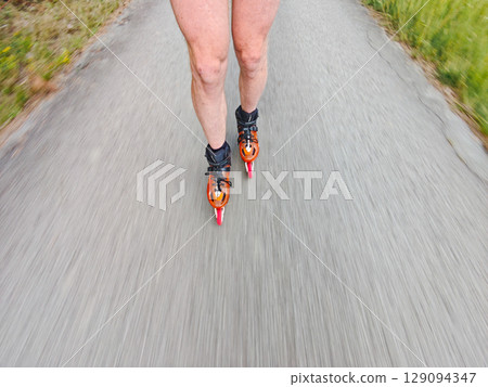 Legs in inline skates boots are moving on asphalt road Legs in inline skates boots are moving on asphalt road 129094347
