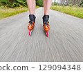 Legs in inline skates boots are moving on asphalt road Legs in inline skates boots are moving on asphalt road 129094348