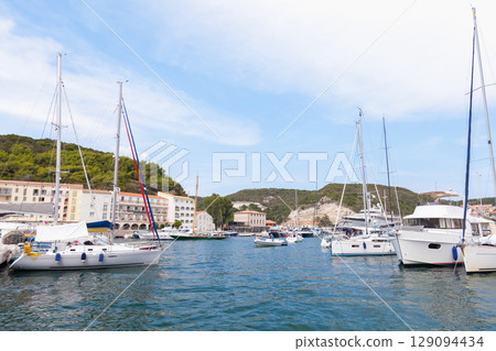 Picturesque Marina with Docked Sailboats and Hills in the Background 129094434