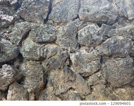 Hard black lava stone rock wall background Hard black lava stone rock wall background 129094601
