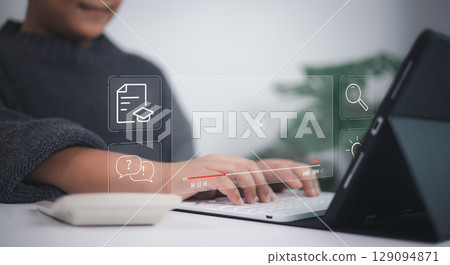 E-learning technology shown as young person types on laptop with virtual icons of education, documents, lightbulb, graduation cap, and question mark, symbolizing modern digital learning. 129094871