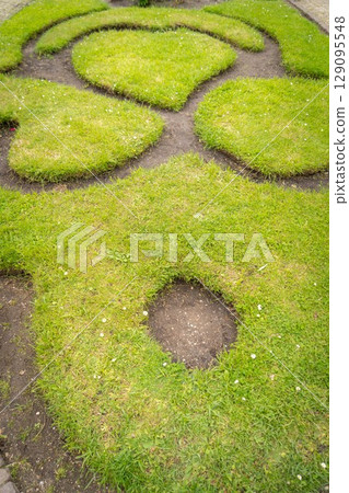 Figure made of green lawn grass in the park, free space. Green grass covered topiary, landscape design. Grass figure, topiary figure. 129095548