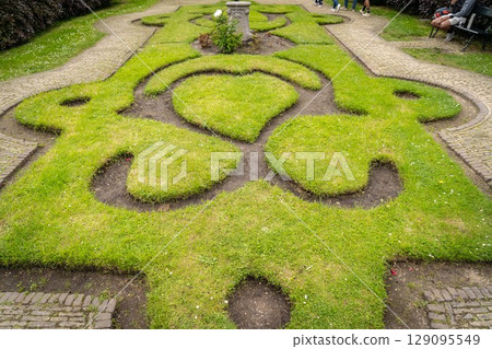 Figure made of green lawn grass in the park, free space. Green grass covered topiary, landscape design. Grass figure, topiary figure. Figure made of green lawn grass in the park, free space. Green grass covered topiary, landscape design. Grass figure, topiary figure. 129095549