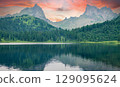 Forest lake at sunset with mountain peaks in the background 129095624
