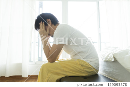 Adult Asian man sitting and feeling depressed on bed. Depression and loneliness concept. 129095878