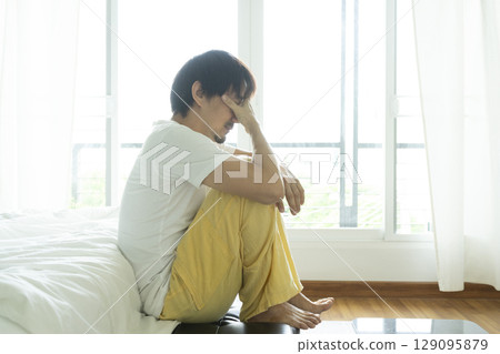 Adult Asian man sitting and feeling depressed on bed. Depression and loneliness concept. 129095879