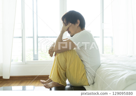 Adult Asian man sitting and feeling depressed on bed. Depression and loneliness concept. 129095880
