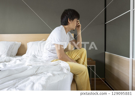 Adult Asian man sitting and feeling depressed on bed. Depression and loneliness concept. 129095881