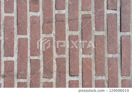 Red brick pattern. Old brick wall with cracks and scratches. Vertical wide brickwall background. Distressed wall with broken bricks texture. Vintage house facade. 129096019