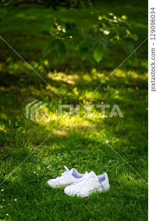 Pair of white sport shoes on grass field Pair of white sport shoes on grass field 129096034