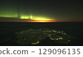 Stunning aurora borealis lighting up the dark night sky above a frozen lake, creating a magical and serene winter landscape 129096135