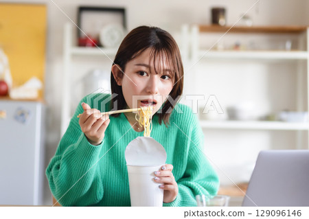 A woman eating cup ramen A woman eating cup ramen 129096146
