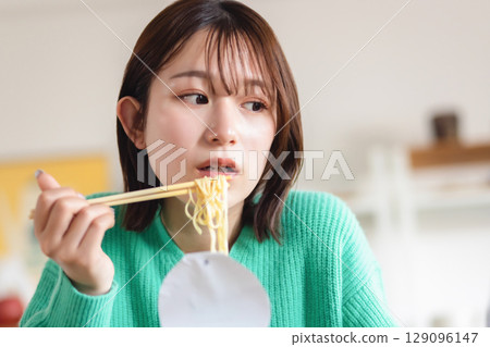 A woman eating cup ramen 129096147