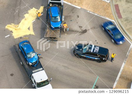 Car accident on American street. Tow truck picking up destroyed car and emergency services helping victims of vehicle crash on road in USA Car accident on American street. Tow truck picking up destroyed car and emergency services helping victims of vehicle crash on road in USA 129096215