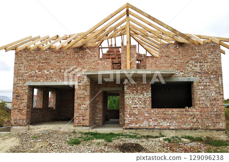 Brick residential house with wooden roof under construction. 129096238