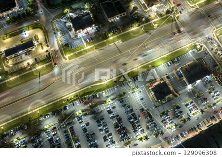 American wide road and strip mall plaza in North Port, Florida. Illuminated town traffic with driving cars at night. USA transportation infrastructure concept 129096308