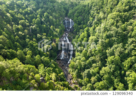 Aerial view of Whitewater Falls in Nantahala National Forest, North Carolina, USA. Clear water falling down from rocky boulders between green lush woods 129096340