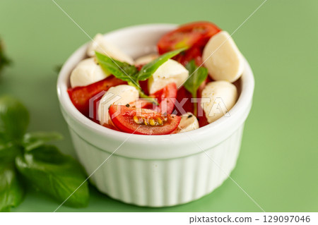 italian caprese salad in a white ceramic bowl on a green background italian caprese salad in a white ceramic bowl on a green background 129097046