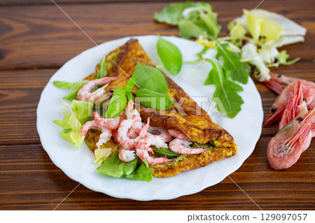 Homemade omelette with seafood on a dark wooden background 129097057