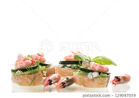 Small canapes with shrimps, salad and cucumbers on a white background 129097059