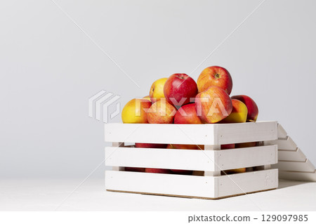 Natural, farm apples in a white wooden box on a light background with copy space. New crop. Selling seasonal, local fruits and vegetables. Soft focus style image 129097985