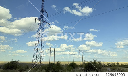 Many high-voltage transmission tower and electricity pylon power lines against blue sky with cloud 129098003