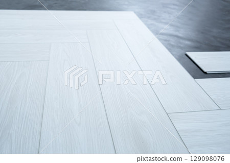 A man lays a quartz laminate on the floor. Renovation, Installation of French herringbone A man lays a quartz laminate on the floor. Renovation, Installation of French herringbone 129098076