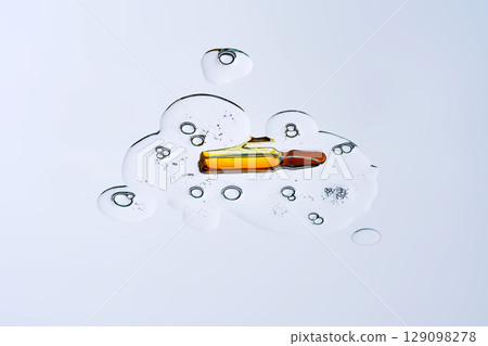 Ampoule in a drop of cosmetic preparation. View from below. 129098278