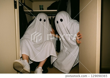 Two Ghosts Peeking from a Closet in Spooky Halloween Scene 129098365