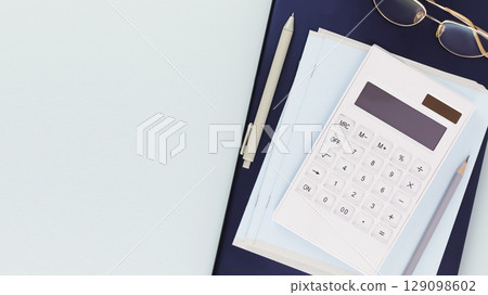 Education banner with school supplies, calculator on tablet with eye glasses on a light blue background with place for text. Online education, e-learning. Work place or education place. Flat lay Education banner with school supplies, calculator on tablet with eye glasses on a light blue background with place for text. Online education, e-learning. Work place or education place. Flat lay 129098602