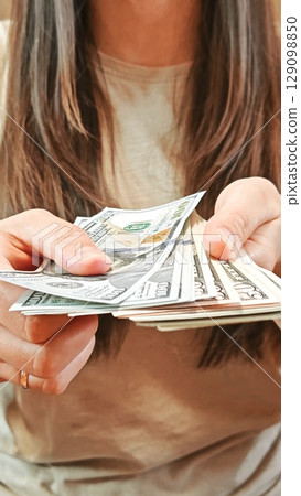 Unrecognizable woman counting US dollar bills. Counting cash bills. 100 USD. Display of US dollar bills in hand. Unrecognizable woman counting US dollar bills. Counting cash bills. 100 USD. Display of US dollar bills in hand. 129098850