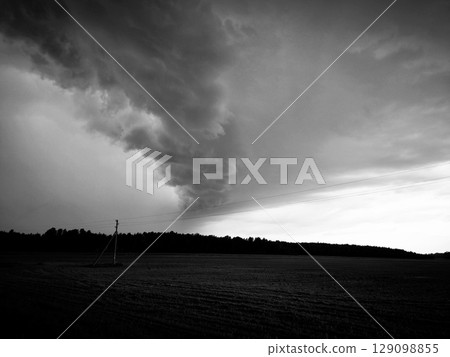 Cloudy landscape of a field. Stormy sky field. Dramatic threatening weather before storm, weather and harvest. Dramatic black and white landscape. 129098855
