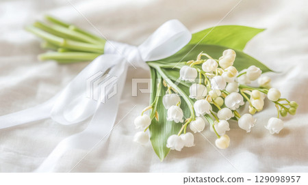 Small bouquet of lily of the valley resting on wooden surface, chrismation symbol 129098957