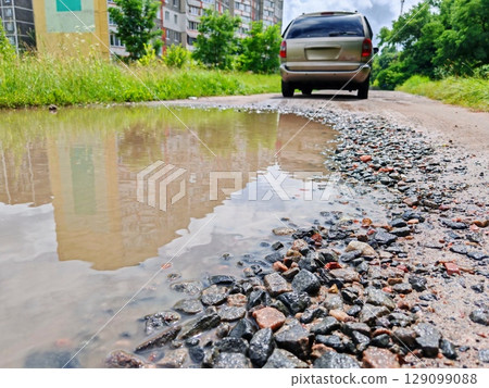 Pothole muddy road and car. 129099088