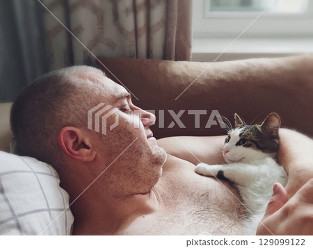 Cat and man, Man cat cuddle. middle-aged man is lying on the couch at home, hugging his pet cat. 129099122