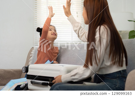 Travel Excitement. A mother and daughter sharing a high-five while preparing for their trip. 129099163