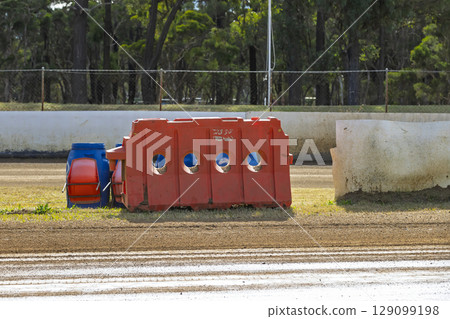 An industrial plastic safety barrier at a dirt race track 129099198