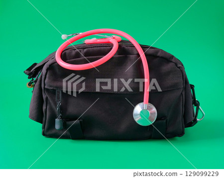 A doctors bag with a stethoscope looped around the handle . A doctors bag with a stethoscope looped around the handle . 129099229