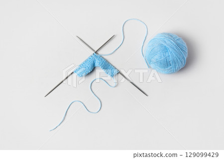 Blue knitted wool on gray background with knitting needles for knitting warm clothes and hobbies needlework 129099429