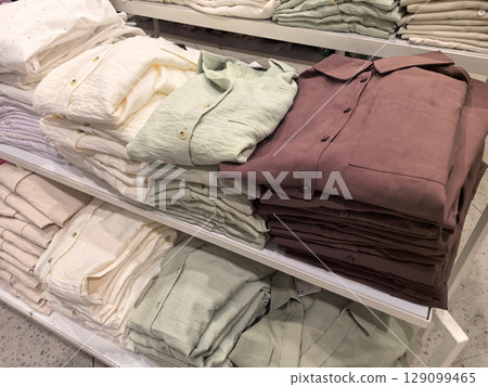 Freshly folded linen shirts neatly organized in a retail setting 129099465