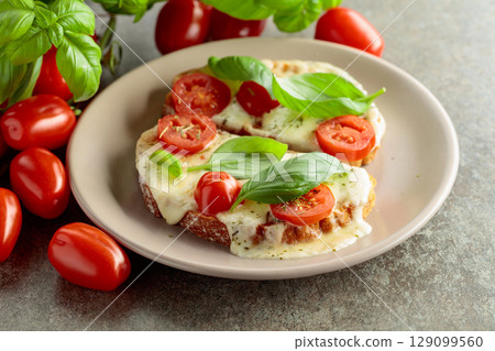 Hot open sandwiches with mozzarella, tomatoes and basil. 129099560
