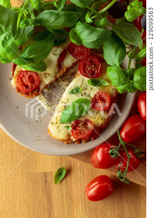 Hot open sandwiches with mozzarella, tomatoes and basil. 129099563