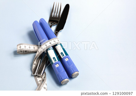 Concept of losing weight with Semaglutid. Knife, fork and syringe wrapped in a measuring tape Concept of losing weight with Semaglutid. Knife, fork and syringe wrapped in a measuring tape 129100097