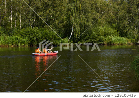 Engaging in a captivating kayaking adventure on a serene river flows through lush nature 129100439